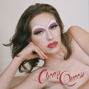 King Princess lounging, wearing audacious makeup