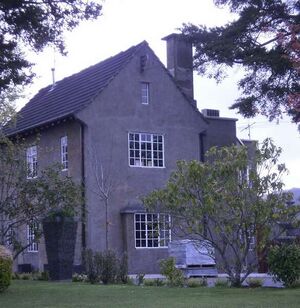 A two-storey concrete house with a large yard