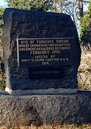 A stone marker with a metal plaque commemorating the Battle of Torrence's Tavern