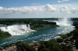 High view of Niagara Falls as viewed from the Canadian side of the river. The image includes American Falls, Bridal Veil Falls, and Horseshoe Falls.